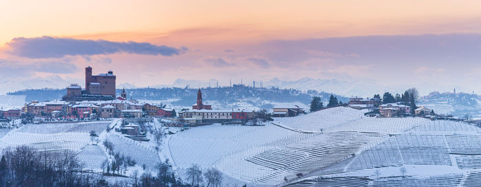 High angle view of snow covered city against sky during sunset