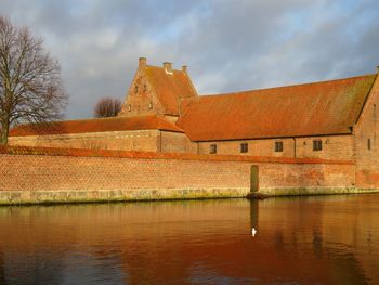 Houses by lake against sky