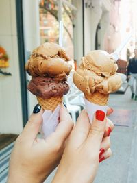 Cropped hands of friends holding ice cream cones on sidewalk