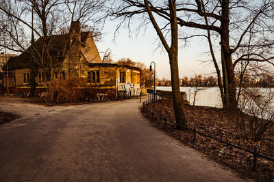 Houses by bare trees against sky