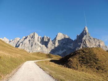 Low angle view of footpath leading to rocky mountains