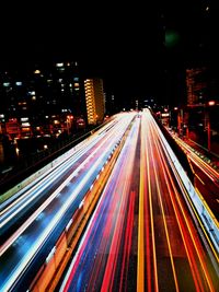 High angle view of light trails on street amidst buildings at night