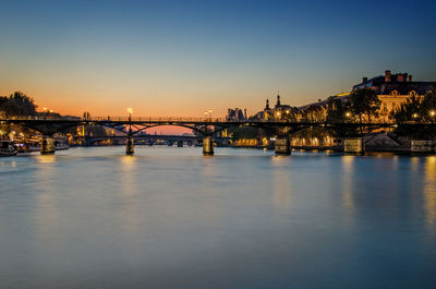 Silhouette bridge over seine river against sky during sunset