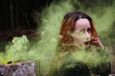 Portrait of young woman smoking amidst smoke