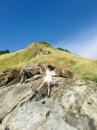 Man standing on rock against clear blue sky