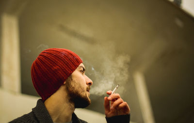 Low angle view of young man smoking cigarette outdoors