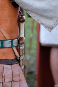 Midsection of person with sword standing outdoors