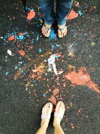 Low section of friends standing on road with paints