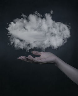 Digital composite image of person holding cloud against black background