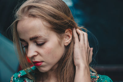 Close-up young woman with hand in hair indoors