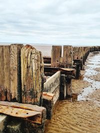 Wooden posts on beach against sky