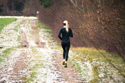 Rear view of woman jogging on road amidst trees