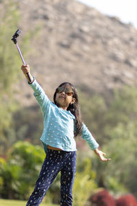 Young woman with arms raised standing outdoors