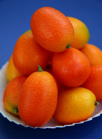 High angle view of kumquats in plate against blue background