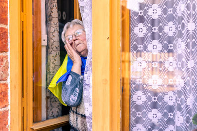 Portrait of young woman looking through window