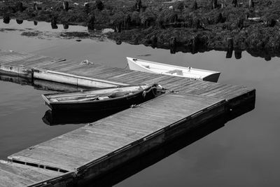 Boats moored by pier on lake against sky