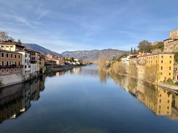Buildings by river against sky