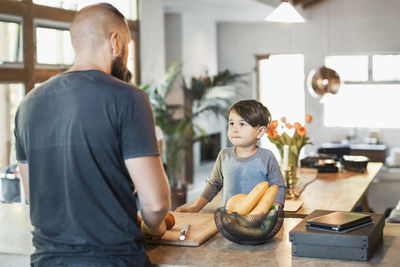 Boy looking at father standing at kitchen counter