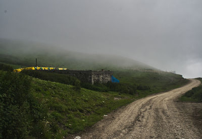 Road amidst field against sky