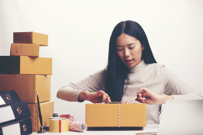 Woman tying cardboard box at home