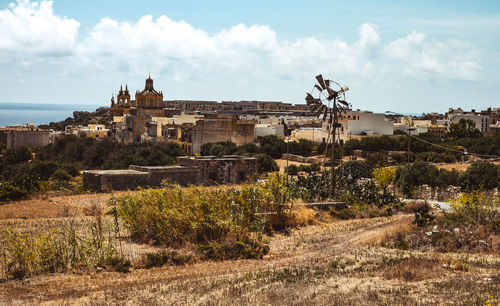 Hill with terraced fields for agriculture, western windmill and old buildings 