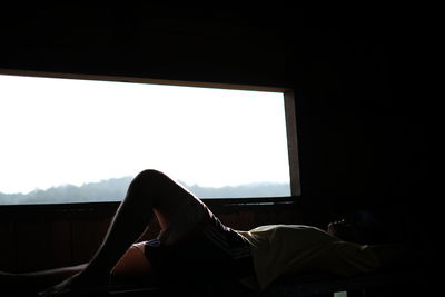 Side view of man relaxing by window