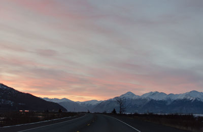 Road by mountains against sky