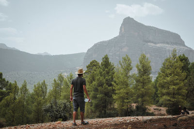 Rear view of man standing on mountain against sky