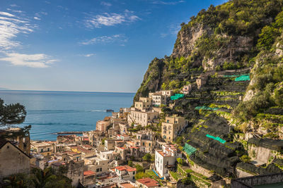 View of buildings on mountain by sea against blue sky during sunny day