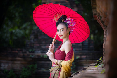 Portrait of young woman in traditional clothing holding umbrella while standing outdoors