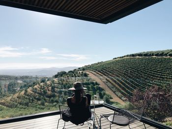 Rear view of woman sitting in balcony against landscape