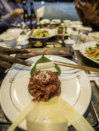 Cropped hand showing peace sign by plate with food at restaurant