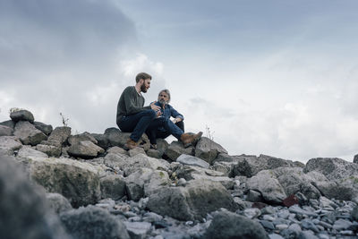 Father and son spending time together outdoors, taking a break, sitting on stones