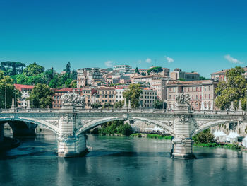 Arch bridge over river in city against blue sky