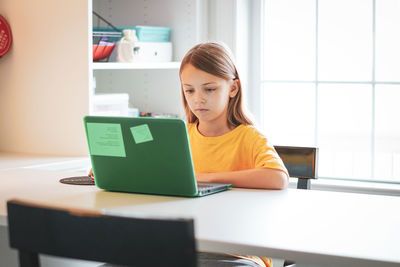 Girl using laptop on table at home