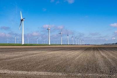 Wind turbines on field against sky