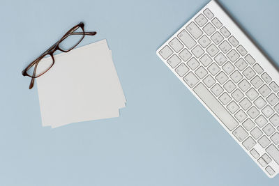 High angle view of papers and eyeglasses by keyboard on table