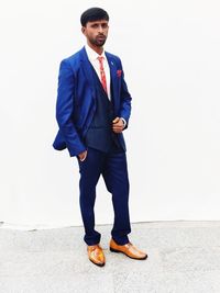Full length portrait of young man standing against white background