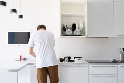 Rear view of man standing on table at home