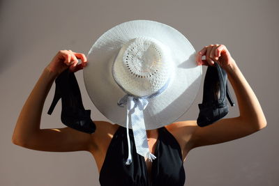 Portrait of woman with hat standing against white background