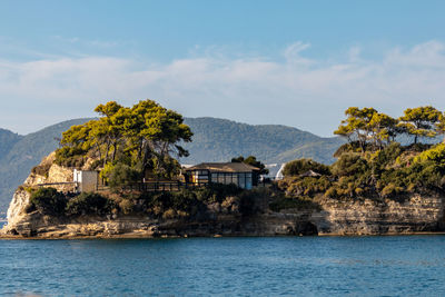 Trees and buildings by sea against sky