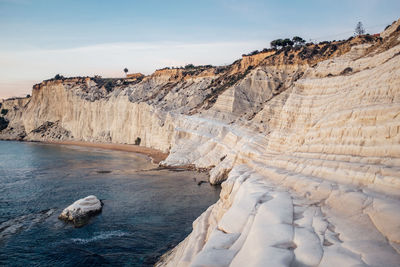 Rock formations by sea at scala dei turchi