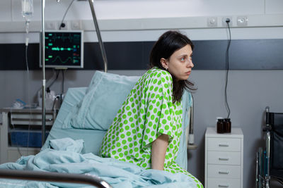 Portrait of young woman sitting on bed at home