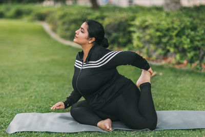 An indian girl practices yoga in a summer park in the afternoon, resting after a hard day. 