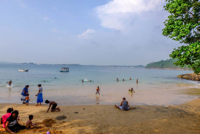 People at beach against sky