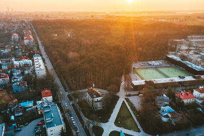 Aerial view of street amidst buildings and forest during sunset