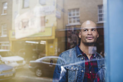 Thoughtful mid adult man in coffee shop seen through window