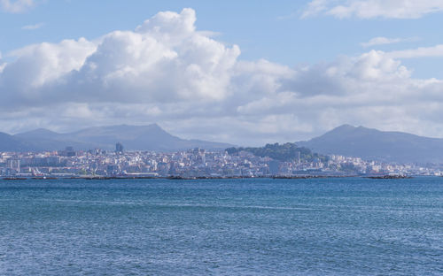 Sea by buildings against sky in city