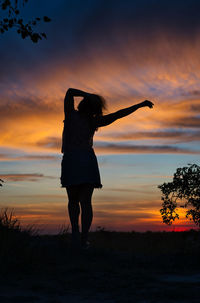 Silhouette woman standing on land against sky during sunset