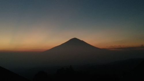 Silhouette of mountain against cloudy sky during sunset